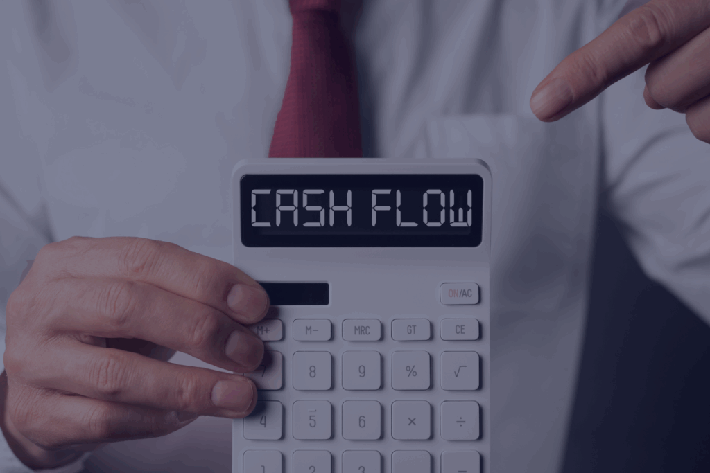 man in white button down and red tie holding calculator that reads cash flow